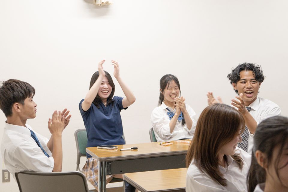 会議室で立ち上がって拍手し、歓声をあげているメンバー