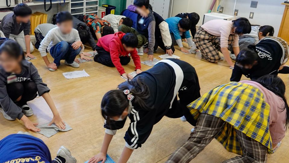 Osouji-tai members scrubbing a classroom floor alongside elementary school children