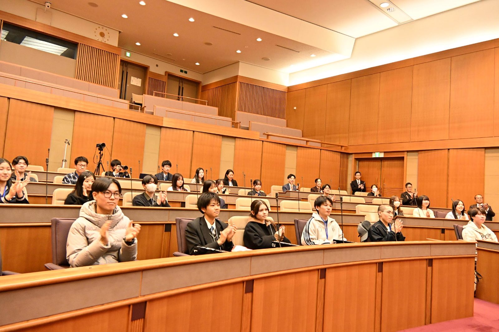 若者議会で、議場の議席から拍手を送る中高生